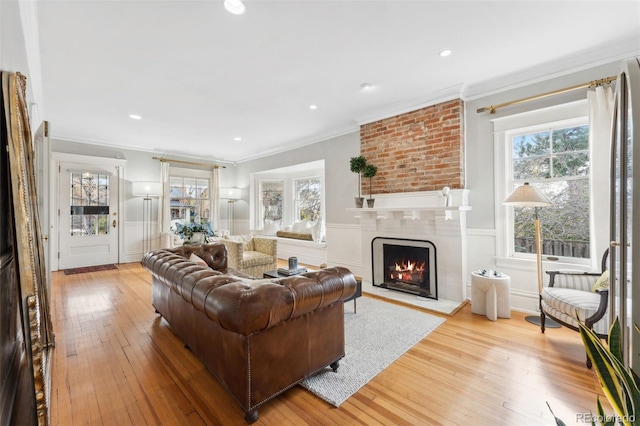 living room featuring ornamental molding, a fireplace, and light hardwood / wood-style flooring