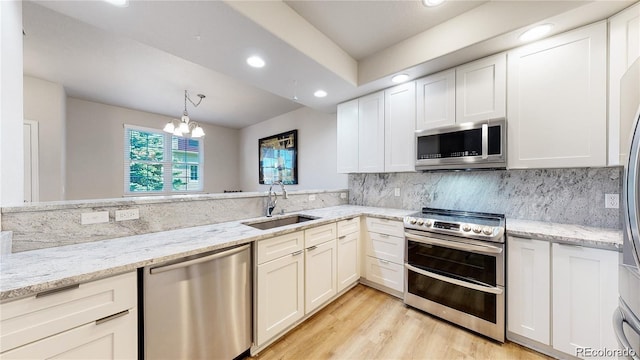 kitchen with stainless steel appliances, white cabinets, a sink, and tasteful backsplash