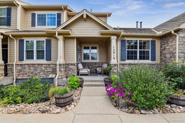 doorway to property featuring stone siding and a porch