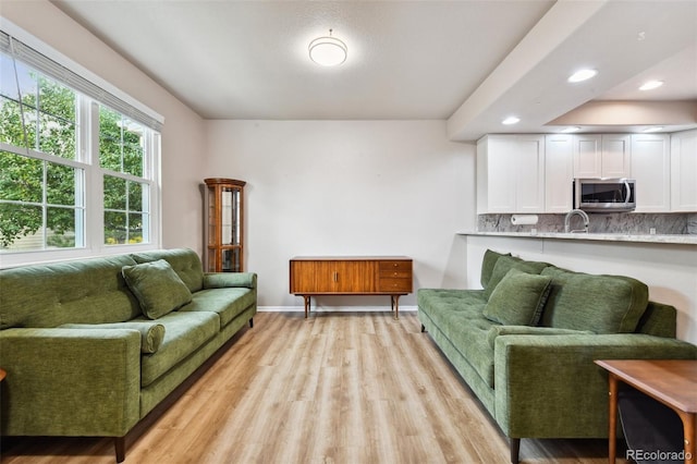 living area with baseboards, recessed lighting, and light wood-style floors