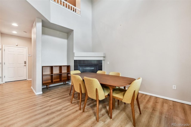 dining area with light wood-type flooring, a fireplace, baseboards, and recessed lighting