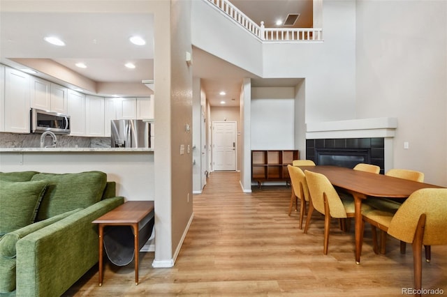 dining room with light wood finished floors, recessed lighting, visible vents, a tile fireplace, and baseboards