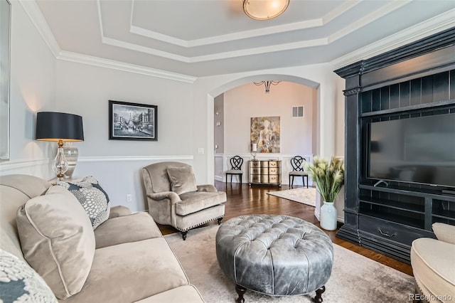 living room with hardwood / wood-style flooring, ornamental molding, and a tray ceiling