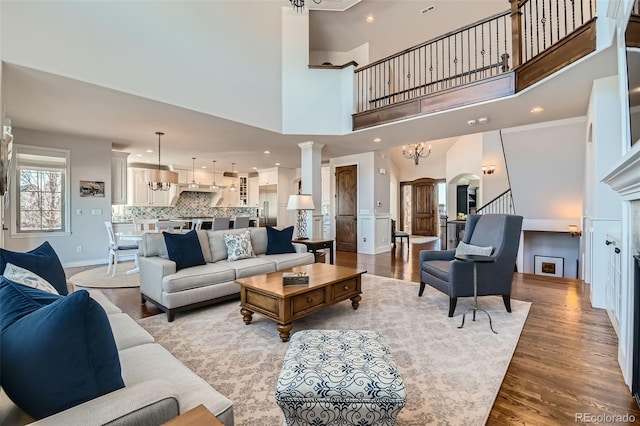 living room with ornate columns, an inviting chandelier, and light wood-type flooring