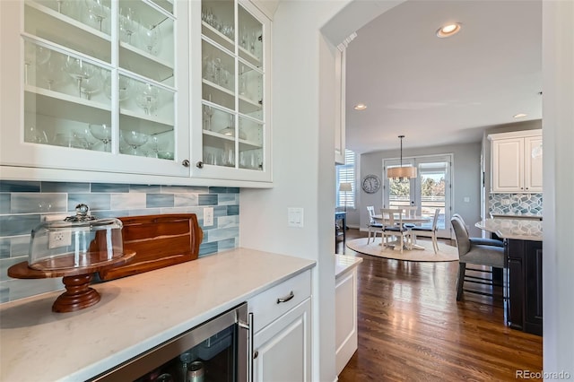 bar featuring white cabinetry, dark hardwood / wood-style flooring, tasteful backsplash, and pendant lighting