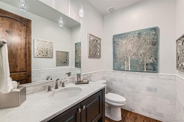 bathroom with vanity, wood-type flooring, tile walls, and toilet