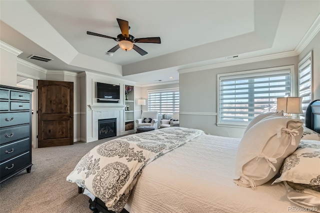 carpeted bedroom with ornamental molding, a raised ceiling, and ceiling fan