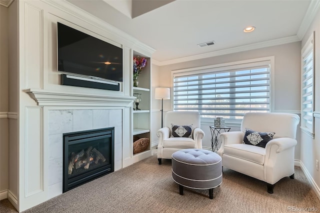 living area with ornamental molding, carpet flooring, and a tile fireplace