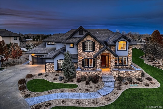 french country style house featuring driveway, an attached garage, a front yard, and stucco siding