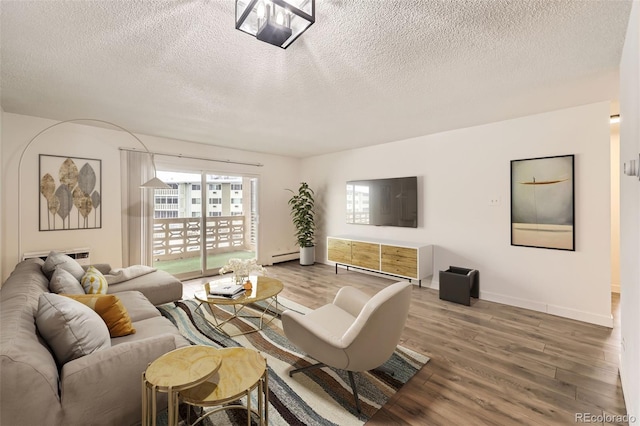 living room with hardwood / wood-style flooring, baseboard heating, and a textured ceiling