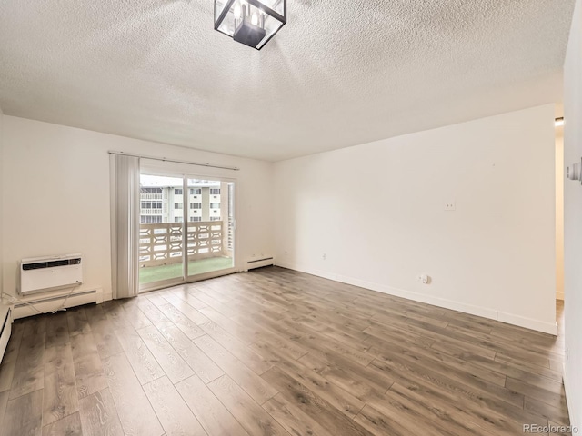 empty room with wood-type flooring, a wall mounted AC, a textured ceiling, and a baseboard radiator