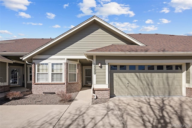 view of front of property featuring an attached garage, concrete driveway, brick siding, and a shingled roof