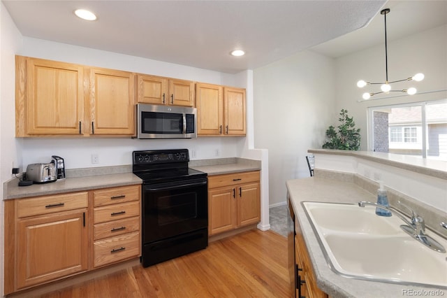 kitchen featuring electric range, light wood-style flooring, stainless steel microwave, decorative light fixtures, and a sink