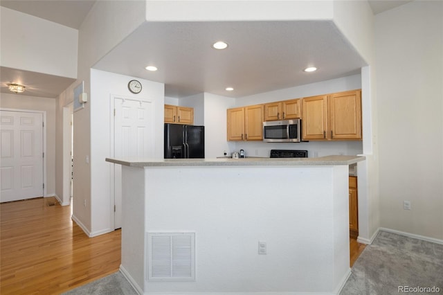 kitchen featuring recessed lighting, visible vents, light countertops, black fridge, and stainless steel microwave