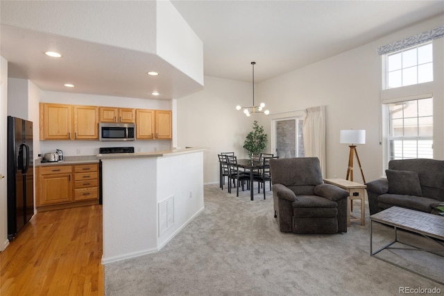 kitchen with visible vents, open floor plan, black fridge, stainless steel microwave, and pendant lighting