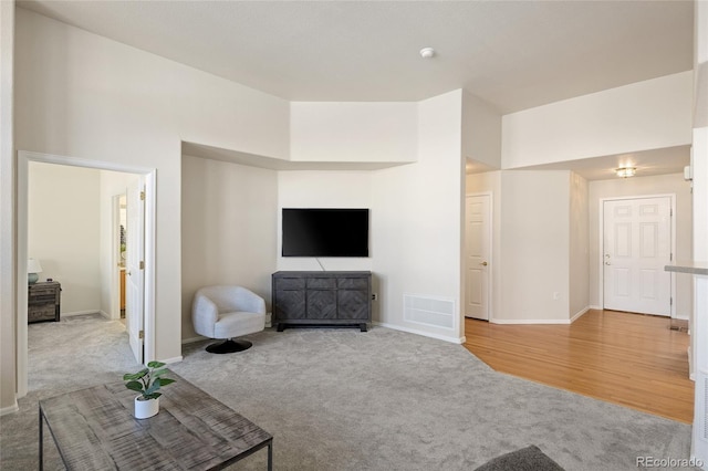 unfurnished living room featuring baseboards, visible vents, and carpet flooring