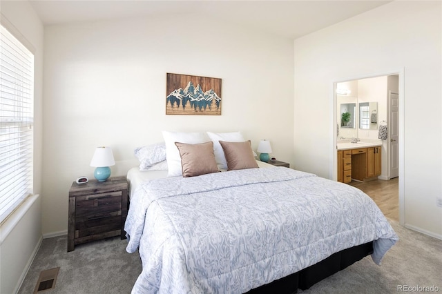 bedroom featuring light carpet, a sink, visible vents, baseboards, and ensuite bath