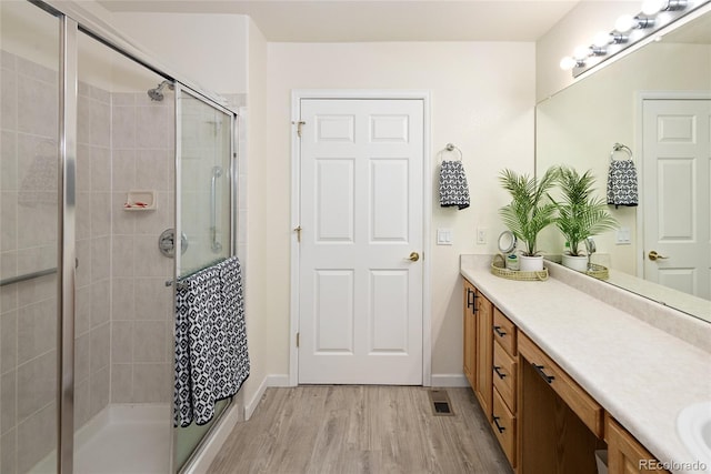 full bath featuring a stall shower, baseboards, visible vents, wood finished floors, and vanity