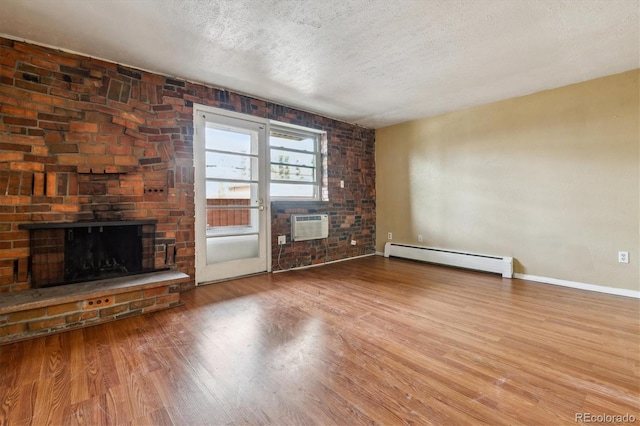 unfurnished living room featuring a brick fireplace, a baseboard heating unit, a textured ceiling, and wood finished floors