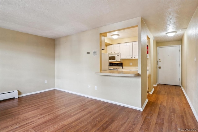 kitchen with a textured ceiling, white cabinetry, wood finished floors, and white appliances
