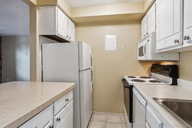 kitchen featuring light tile patterned floors, baseboards, white appliances, tile counters, and white cabinetry