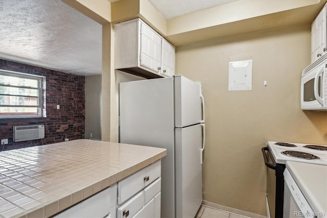 kitchen with white appliances, a textured ceiling, a wall unit AC, and tile counters