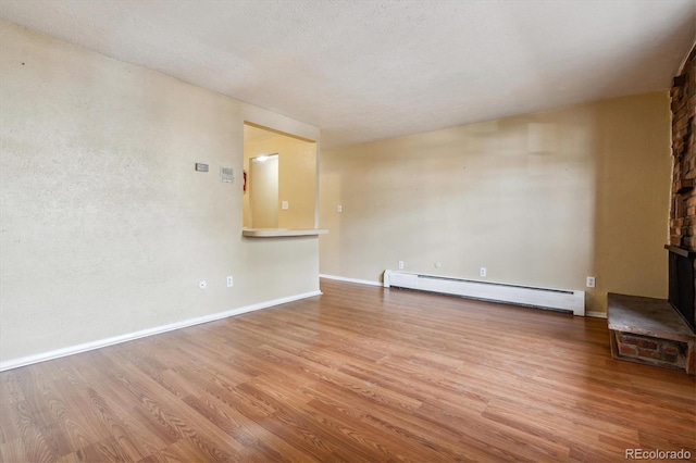 unfurnished living room featuring wood finished floors, a baseboard heating unit, and baseboards