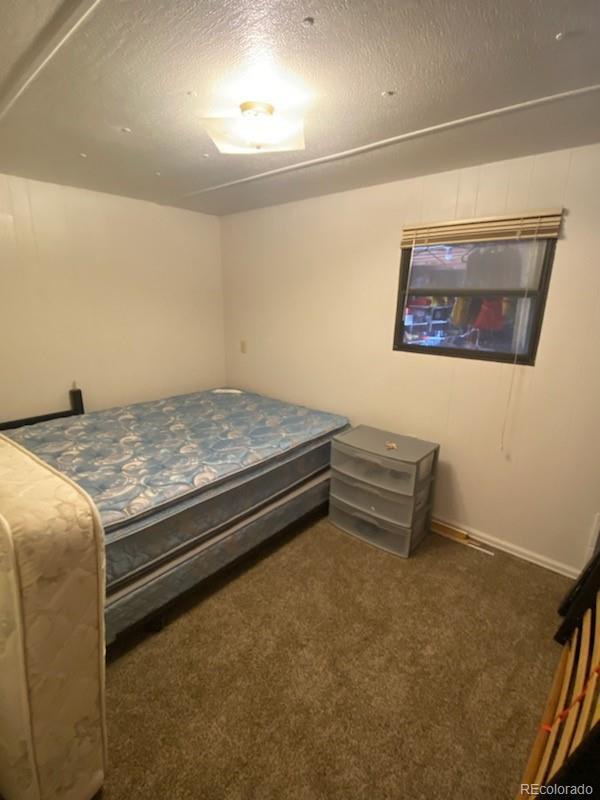 bedroom with dark colored carpet and a textured ceiling