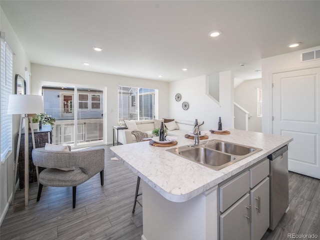 kitchen featuring sink, dark hardwood / wood-style floors, gray cabinets, dishwasher, and an island with sink