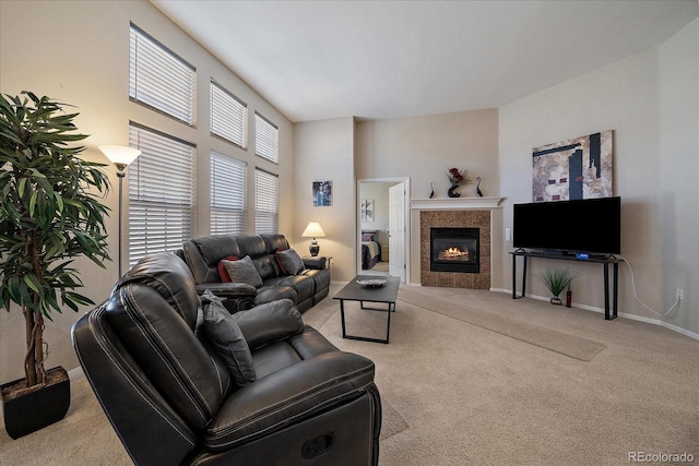 living room featuring baseboards, carpet flooring, and a tile fireplace