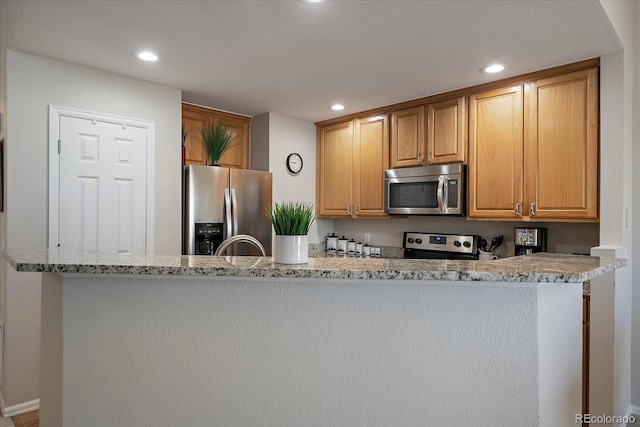 kitchen with appliances with stainless steel finishes, light stone countertops, and recessed lighting