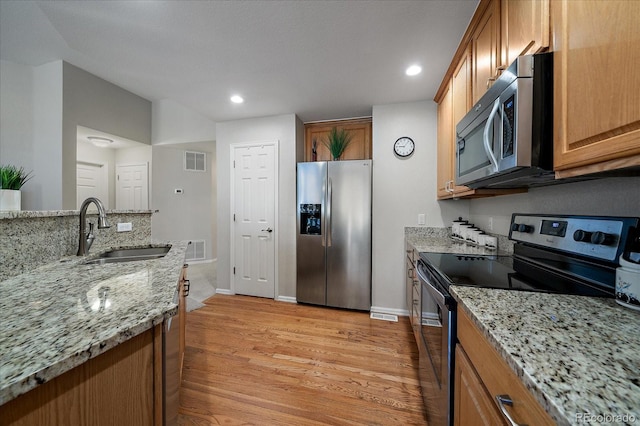 kitchen with stainless steel appliances, light wood-style flooring, a sink, and visible vents