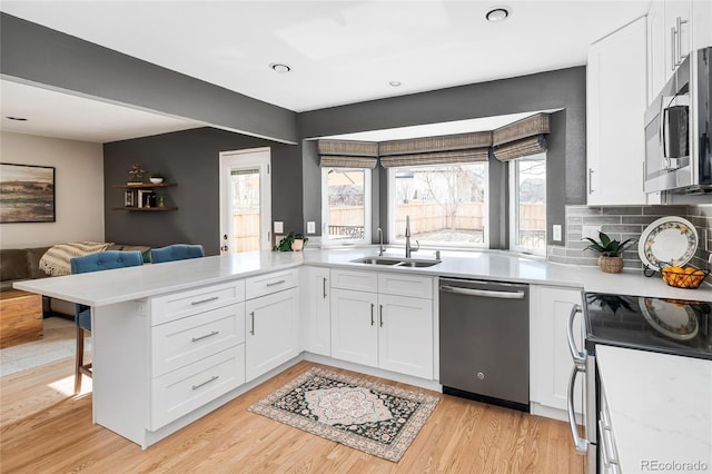 kitchen featuring a sink, appliances with stainless steel finishes, white cabinets, and light countertops