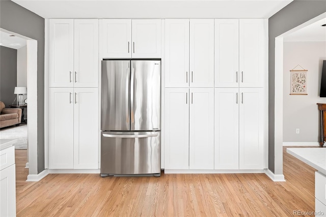 kitchen with white cabinetry, light wood finished floors, and freestanding refrigerator