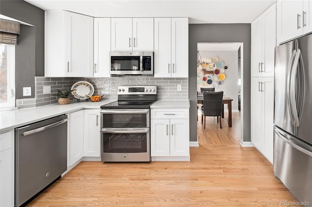 kitchen featuring light wood-style flooring, white cabinetry, stainless steel appliances, and light countertops