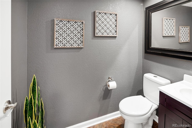 bathroom with toilet, vanity, and a textured wall