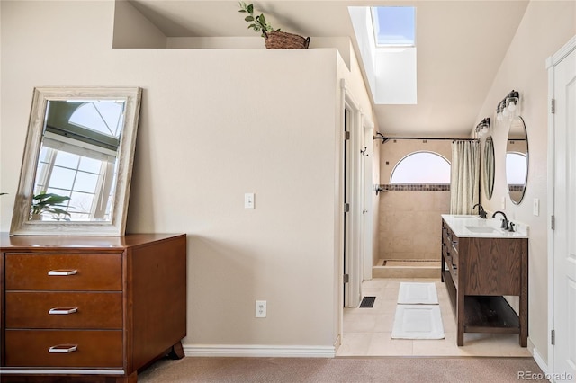 full bath with visible vents, baseboards, a tile shower, a skylight, and vanity