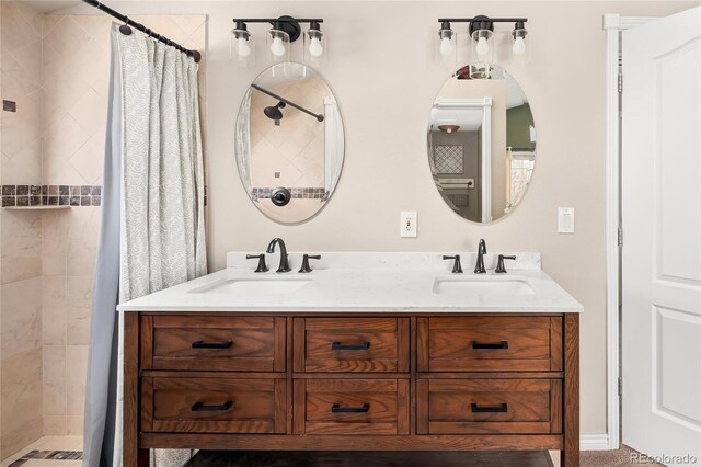 bathroom with double vanity, tiled shower, and a sink