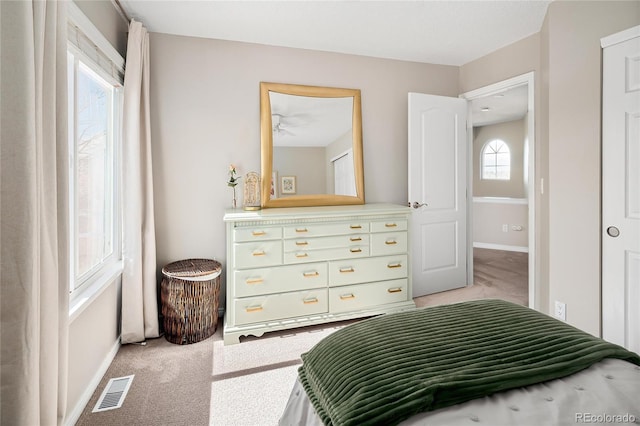 bedroom with visible vents, light carpet, and baseboards