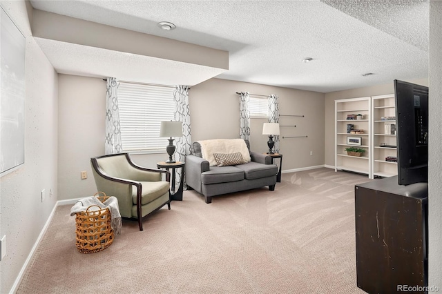 sitting room with light carpet, a textured ceiling, and baseboards