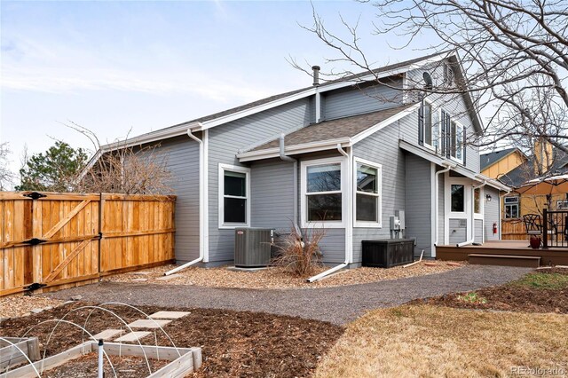 view of side of property with central air condition unit, a vegetable garden, a deck, and fence