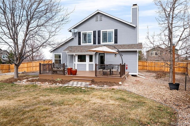 back of property with a wooden deck, a fenced backyard, a lawn, and a chimney