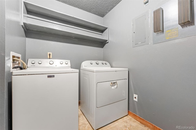 laundry area featuring washing machine and clothes dryer, electric panel, and a textured ceiling