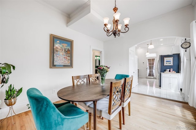 3106 N Franklin St, Denver, CO 80205 - dining room featuring arched walkways, light wood-style flooring, a chandelier, and crown molding