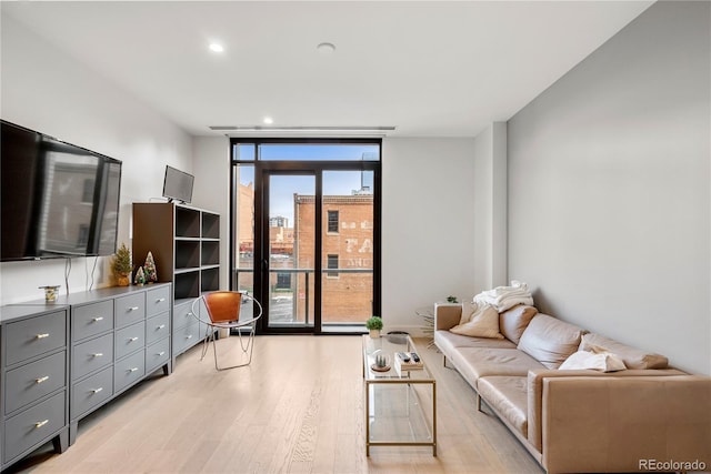 living area featuring a wall of windows, light wood-type flooring, and recessed lighting