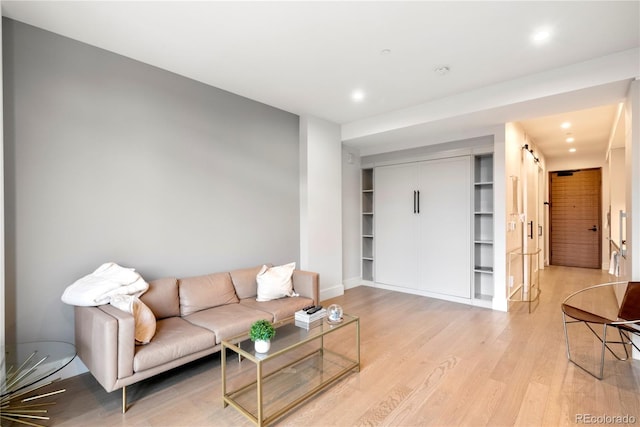 living area with baseboards, light wood-style flooring, and recessed lighting