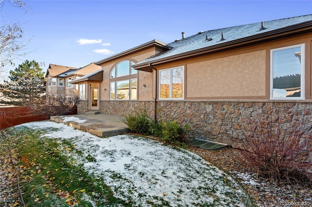 snow covered rear of property featuring a patio area