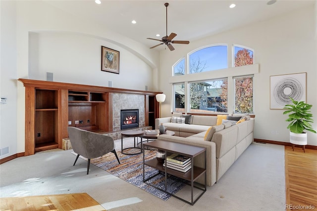 carpeted living room featuring ceiling fan and a tiled fireplace