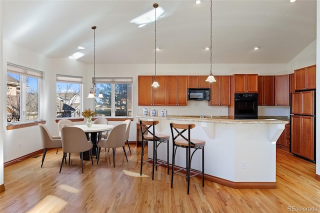 kitchen with decorative light fixtures, lofted ceiling, a kitchen island, and black appliances