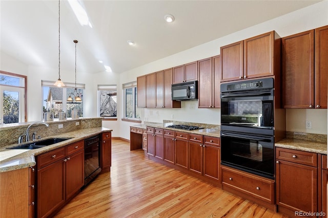 kitchen with a healthy amount of sunlight, decorative light fixtures, black appliances, light stone counters, and sink